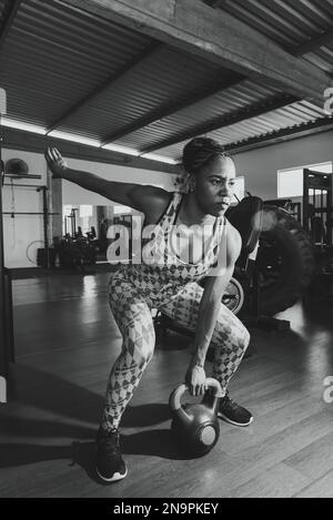 Determined Woman Doing Squat Exercises With Kettlebell. Spine strengthening. Stock Photo