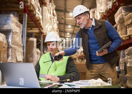 Portrait of two male workers using laptop in warehouse while managing distribution Stock Photo