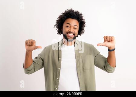 Attractive 30s african-american man pointing thumbs himself proud winner isolated on white, positive proud curly guy with white toothy smile offers to choose his candidacy Stock Photo