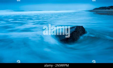 Surf swirling around a rock by the shore at dawn on Marconi Beach; Welfleet, Massachusetts, United States of America Stock Photo