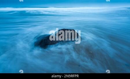 Surf swirling around a rock by the shore at dawn on Marconi Beach; Welfleet, Massachusetts, United States of America Stock Photo