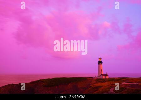 Dramatic pink sky at sunrise over Yaquina Head Light on the Oregon Coast; Newport, Oregon, United States of America Stock Photo