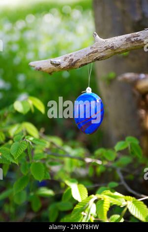Painted easter egg hanging from a tree in the forest Stock Photo