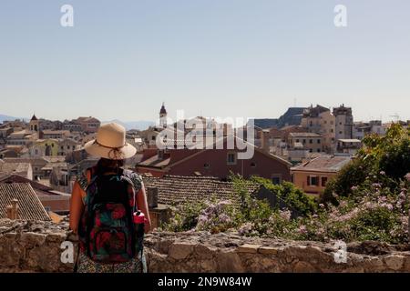 Tourist woman wearing a hat enjoying the view on a sunny day. Exploring Corfu in the summer time on a Greek tourist holiday Stock Photo