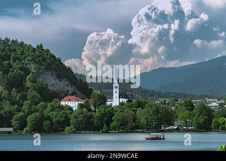 Bled lake with a church Zupnijska cerkev svetega Martina- Church of St. Martina, Bled, with a background of white clouds in summer day time Stock Photo