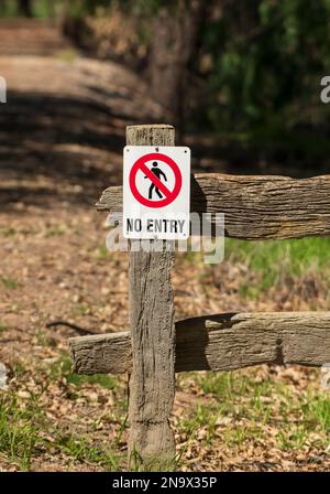 No entry sign on a wooden fence post restricting entry to private land. Stock Photo