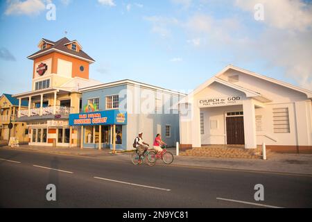 Waterfront businesses and cyclists in George Town, Cayman Islands; George Town, Grand Cayman, Cayman Islands Stock Photo