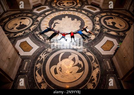 Tour group lays in a row on the decorative Rotunda floor in the Nebraska State Capitol and looks up to admire the ceiling Stock Photo