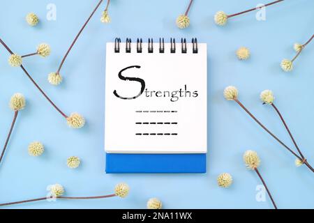 List of personal strengths written on blue notepad. Personality development beautiful flat lay composition. Stock Photo