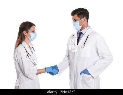 Doctors in medical face masks shaking hands on white background Stock Photo