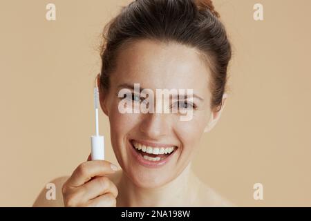 middle aged woman with brow brush isolated on beige background. Stock Photo