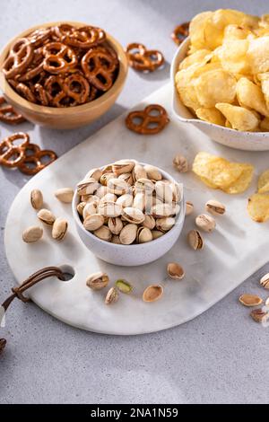 Variety of salty snacks on the table with pretzels, pistachios and potato chips, snacks that go well with beer Stock Photo