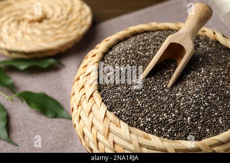 Wicker box with chia seeds and scoop on table, closeup Stock Photo