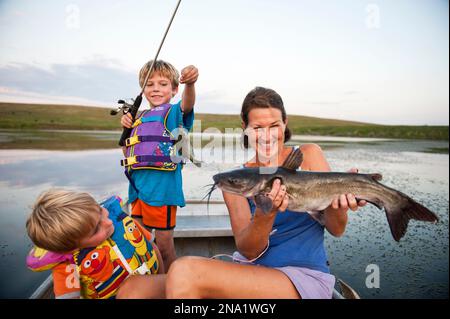 Three brothers fishing, sitting on the edge of a local pond. Their 'less  than enthusiastic' expressions say it all; bored and cold! Stock Photo -  Alamy