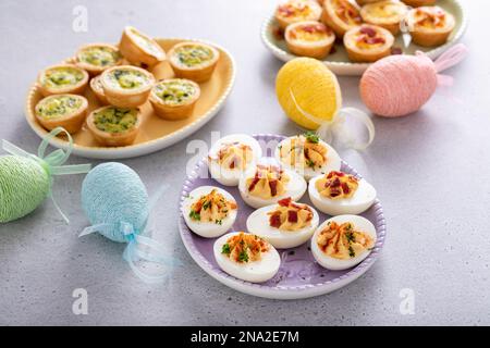 Deviled eggs and mini quiches, appetizers for Easter brunch Stock Photo