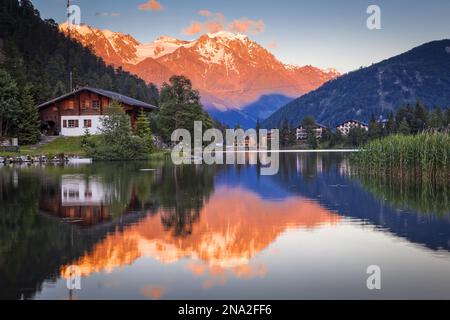 Pastel-coloured sunset glow on the mountains reflecting on Champex Lake; Champex, Valais, Switzerland Stock Photo