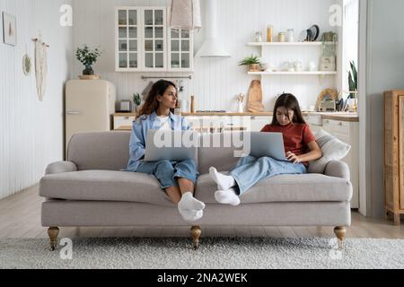Family mother and daughter using laptops together while sitting on sofa in living room at home Stock Photo