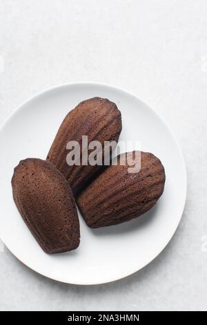 Chocolate madeleines on a ceramic plate, plain chocolate madeleine cake or cookies Stock Photo