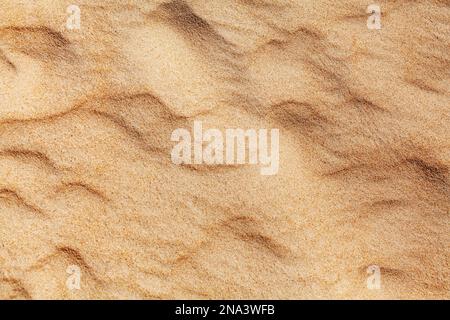 Wavy yellow sand texture closeup background, sandy waves pattern, natural beige sand grains backdrop, rippled dry sand surface top view, desert dune Stock Photo