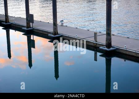 Clouds and wooden pylons reflected in still water Stock Photo