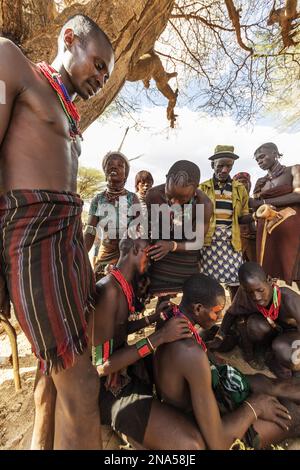 Hamer men getting their faces painted ahead of a bull jumping ceremony, which initiates a boy into manhood, in the village of Asile Stock Photo