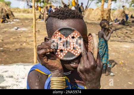 Mursi boy showing a lip plate in a village in Mago National Park; Omo Valley, Ethiopia Stock Photo