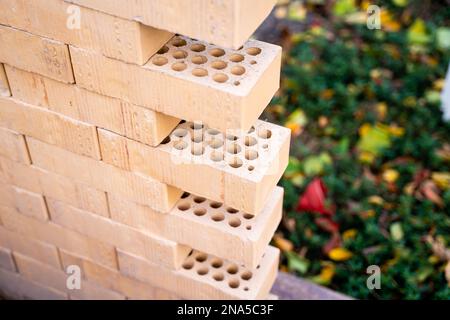 Decorative perforated bricks of light brown color stacked close-up on a blurred background. An example of brickwork Stock Photo