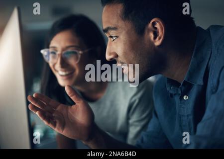 Follow MY lead. two young workers using a laptop in a modern office. Stock Photo