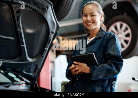 Did you know your car needs regular servicing to keep it running smoothly. a female mechanic holding a digital tablet while working in an auto repair Stock Photo