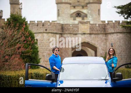 Couple traveling in camper van stop for a selfie in front of Eastnor Castle in Ledbury; Eastnor, Herefordshire, England, UK Stock Photo