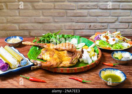 Grilled chicken in vietnamese style with colorful rice in bamboo, and boiled eggs on wooden table Stock Photo