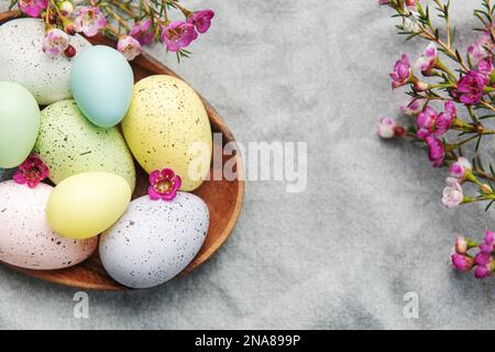 Easter decor. Colored Easter eggs on a wooden plate on the table. The concept of preparing for the celebration. Stock Photo