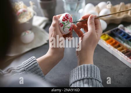 Woman painting Easter egg at black table, closeup Stock Photo