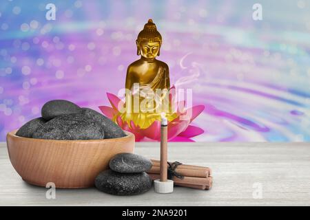 Composition with smoldering incense stick on wooden table and Buddha figure on background Stock Photo