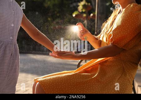 Mother applying insect repellent onto girl's hand outdoors, closeup Stock Photo