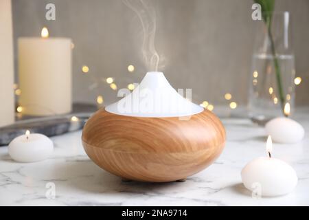 Aroma oil diffuser and burning candles on white marble table Stock Photo