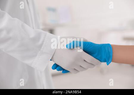 Doctors in medical gloves giving handshake at hospital, closeup Stock Photo