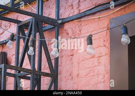 Garlands of simple light bulbs on the background of a brick painted wall Stock Photo