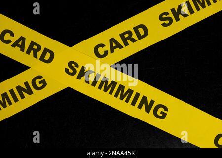 Card skimming cybercrime and theft alert, caution and warning concept. Yellow barricade tape with word in dark black background. Stock Photo