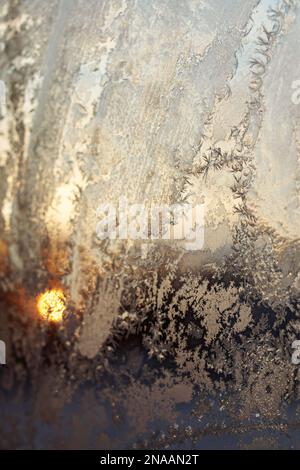Frosty patterns on glass against the background of the morning sun Stock Photo