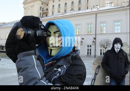 A man wearing a Guy Fawkes mask makes photos a protest against the Anti-Counterfeiting Trade Agreement, or ACTA, front of the Presidential Palace in Warsaw, Poland, Saturday, Feb. 11, 2012.