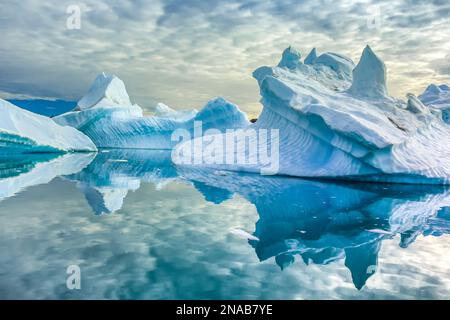 Sculpted icebergs and reflections in Semerlik Fjord. Stock Photo