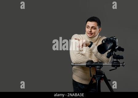 photographer in sweater near digital camera on tripod Stock Photo
