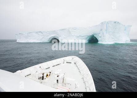 Bow of an expedition ship near a tabular iceberg in Antarctica; South Orkney Islands, Antarctica Stock Photo