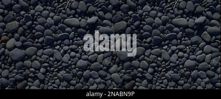 Black pebbles on a beach. background texture. Banner wallpaper Stock Photo