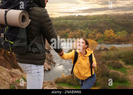 Couple of hikers with backpacks climbing up mountains Stock Photo