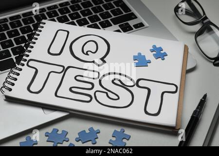 Notebook with words IQ Test, puzzles and laptop on white table Stock Photo