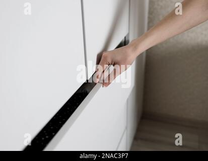 Woman open shelf, pull open drawer wooden in cabinet with clothes Stock Photo