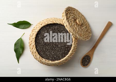 Wicker box and spoon with chia seeds on white wooden table, flat lay Stock Photo