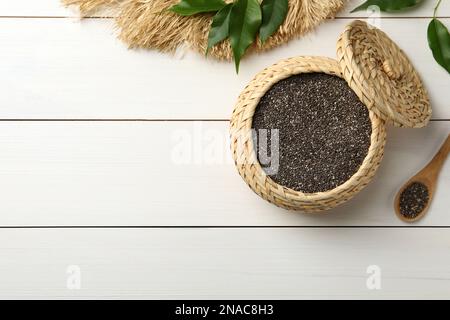 Wicker box and spoon with chia seeds on white wooden table, flat lay. Space for text Stock Photo